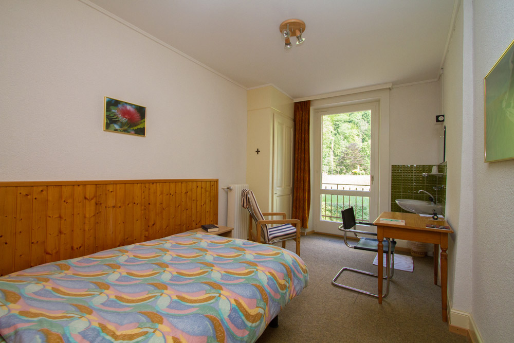 Chambre individuelle du Foyer — lit, bureau, lavabo et balcon donnant sur la verdure