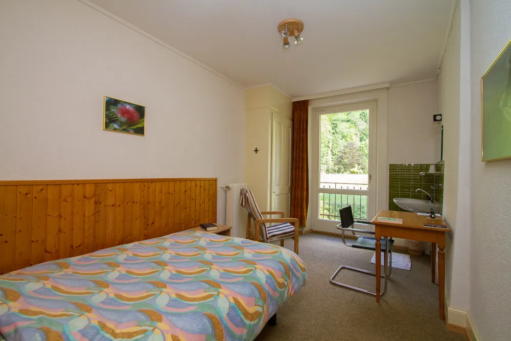 Chambre individuelle du Foyer — lit, bureau, lavabo et balcon sur la verdure